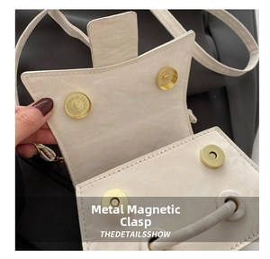 Detail shot of the golden magnetic closure on a minimalist white leather crossbody bag