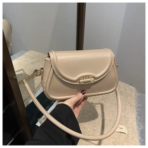 Detail view of beige leather handbag featuring a stylish gold cylindrical twist lock