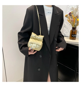 Close-up of golden quilted bag with large bow detail and metal chain strap on model