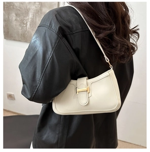 Gros plan sur le sac baguette en cuir crème avec boucle dorée et bandoulière