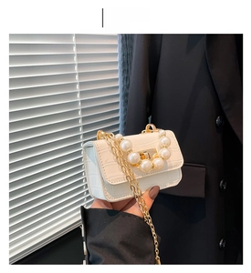 Détail du mini sac blanc motif crocodile avec poignée en perles et bandoulière dorée