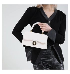 Détail d'un sac à main blanc en cuir ciré avec un fermoir rotatif en métal doré chic