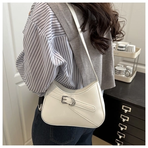 Detail of white half-moon underarm bag featuring a metallic buckle and smooth leather finish