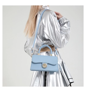 Détail du sac à main en cuir bleu clair avec fermoir doré et poignée supérieure ronde