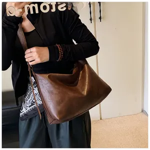Grand sac fourre-tout marron foncé en cuir souple porté par un mannequin en situation