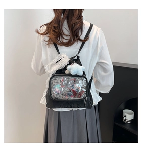 Detail of black ita bag featuring a large clear PVC window and anime badges with lace trim