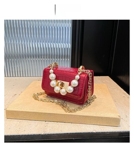 Détail d'un mini sac rouge texture crocodile avec poignée en perles et chaîne dorée