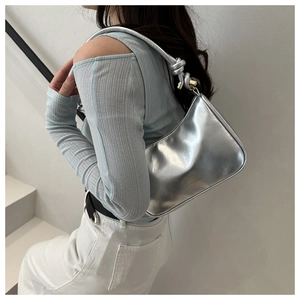 Detail of silver metallic shoulder bag with knotted metal hardware and fashion text