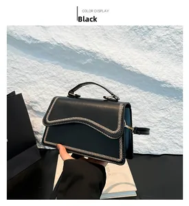Detail of black PU leather bag with unique wavy edges and white decorative stitching