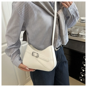 Close-up of white crescent crossbody bag with decorative buckle on a model