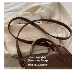Detail of vintage brown crocodile embossed leather bag with adjustable strap and handle