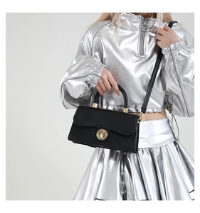 Détail du sac bandoulière noir avec boucle dorée ronde et texture en cuir mat élégant