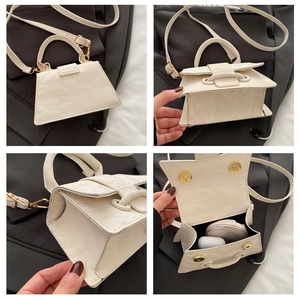 Macro details of white textured leather handbag showing pleats, strap, and interior capacity