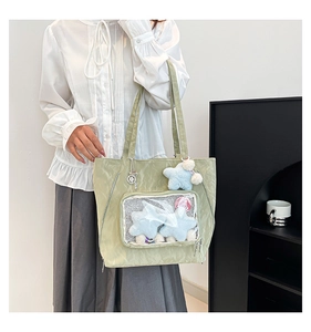 Detail of light green nylon ita bag featuring a clear window with plush star accessories