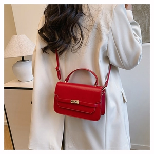 Detailed view of a red leather handbag with gold metal clasp on a model waist
