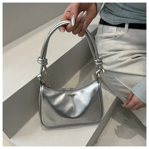 Detail of silver metallic shoulder bag featuring double knot handles and golden hardware