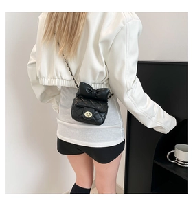 Detail van zwarte gewatteerde mini-crossbodytas met lederen kettingriem en strik