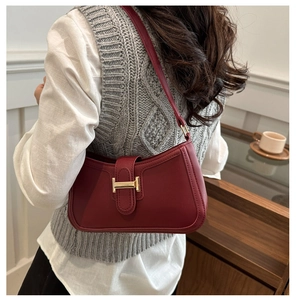 Détail du sac croissant bordeaux avec boucle H dorée sur une texture de cuir lisse