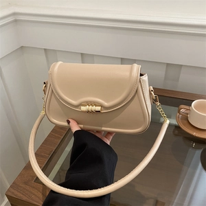 Fashionable apricot leather shoulder bag with gold clasp shown in a lifestyle cafe setting