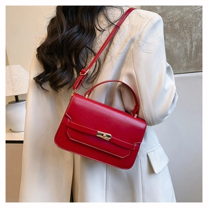 Detail showing red leather handbag with gold twist lock on light beige coat