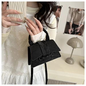 Detail of black mini crossbody bag with metal eyelets and velvety texture finish