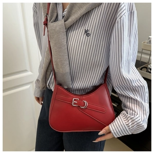 Detail of red leather shoulder bag with silver buckle worn over striped shirt