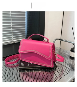 Detail view of rose red shoulder bag featuring wavy flap and metal chain woven edge