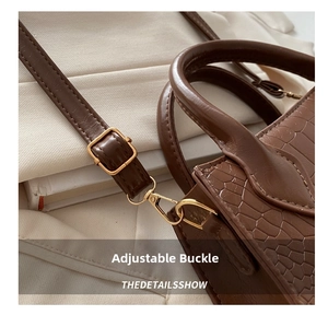 Close-up of golden adjustable buckle on brown crocodile texture leather handbag