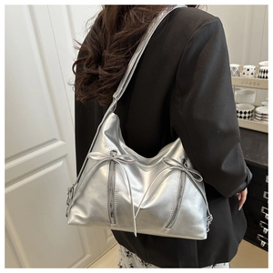 Detailansicht der silbernen Metallic-Schultertasche mit Schleifen und Reißverschlüssen