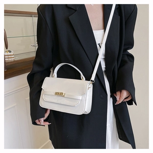 Detail of white glossy leather handbag with gold metal clasp and detachable strap
