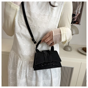 Detail of a matte black trapezoid crossbody bag with elegant lace-up strap decoration