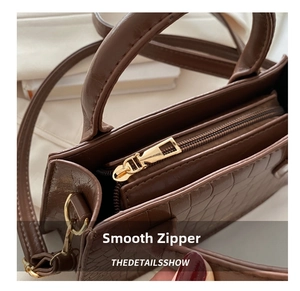 Detailed close-up of dark brown crocodile texture leather bag with smooth golden zipper