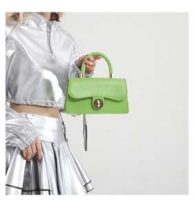 Détail du sac à main vert carré avec boucle dorée et tenue de mode métallique