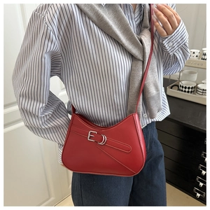 Detail of red crescent leather bag with silver buckle and sleek streamlined curve design