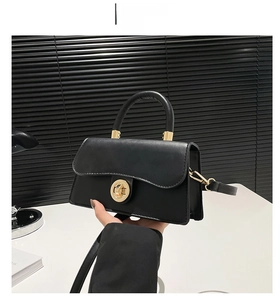 Vue détaillée du sac à main noir avec son fermoir en métal rond et sa poignée fixe