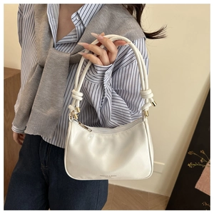 Detail shot of white PU leather bag with knotted handle and elegant zipper closure