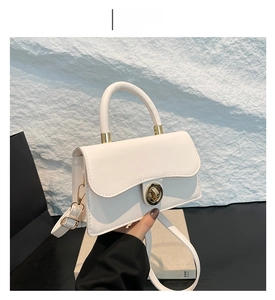 Détail du sac à main blanc en cuir avec fermoir rotatif en métal doré et poignée chic