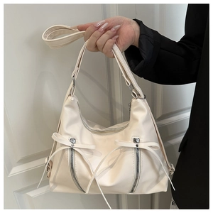 Detailansicht der cremefarbenen Ledertasche mit Schleifenakzenten und Reißverschlüssen