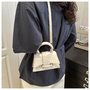 Close-up of minimalist ivory handbag with unique ring buckle detail and smooth finish