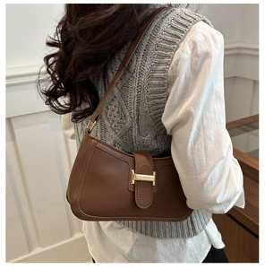 Détail du sac demi-lune en cuir marron foncé avec boucle H dorée sur bandoulière fine