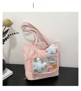 Detail of pink nylon tote bag with transparent mesh pocket and blue star plush charm