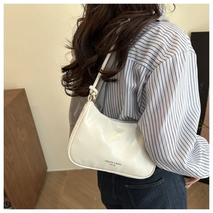 Side view of model wearing a minimalist beige leather half-moon baguette shoulder bag