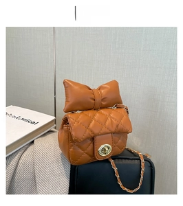 Detail van de karamelkleurige gewatteerde mini-tas met gouden ketting en leren strik
