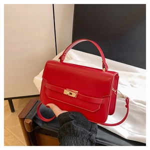 Detailed view of red leather crossbody bag featuring gold twist lock and top handle