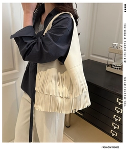 Detailed view of cream-colored fringed shoulder bag with lychee grain leather texture