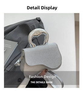 Detail of silver handbag with glitter texture and curved metallic handle on blazer