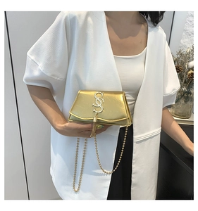 Détail d'un mini sac doré à chaîne avec glands métalliques et logo SS argenté chic