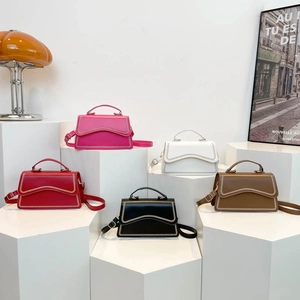 Minimalist crossbody bags with wavy woven edges in five colors on geometric pedestals