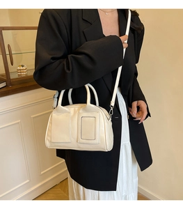 Détail d'un sac Boston blanc crème avec ferrures argentées sur un mannequin en blazer