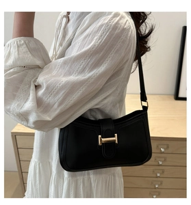 Détail du sac à bandoulière en cuir noir avec boucle métallique dorée minimaliste